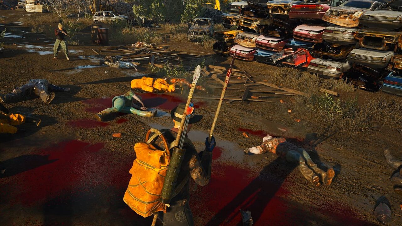 Una chatarrería con coches apilados al fondo y varios cuerpos tendidos entre charcos de sangre, con un jugador con mochila naranja y una lanza en primer plano