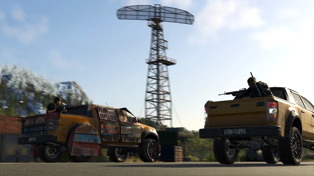 Dos camionetas, una amarilla y una con un tirador armado, junto a una torre de radio sobre una explanada, con colinas nevadas al fondo